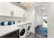 Modern laundry room with white cabinets and a view of a hallway at 1155 N Gulfstream Ave # 908, Sarasota, FL 34236