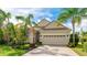 Tan house with a two-car garage, stone accents, and tropical landscaping at 12018 Thornhill Ct, Lakewood Ranch, FL 34202