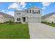 Two-story house with gray siding, two-car garage, and a landscaped yard at 5829 Flagstone Trl, Palmetto, FL 34221