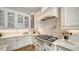 A kitchen features white cabinetry, a large range with vent hood, and tile backsplash at 1682 Hawthorne St, Sarasota, FL 34239