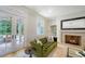 Elegant living room with a fireplace, green sofa, and French doors leading to a scenic outdoor area at 1682 Hawthorne St, Sarasota, FL 34239