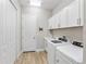 Well-lit laundry room with modern washer, dryer, cabinets, sink, and wood-look tile floors at 4906 Lighthouse Bay Ln, Bradenton, FL 34211