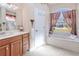 Bright bathroom with a soaking tub and a view, alongside a vanity with a mirror at 5352 Layton Dr, Venice, FL 34293