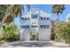 Stunning three-story home featuring blue awnings, a two-car garage, and tropical landscaping at 681 Casey Key Rd, Nokomis, FL 34275
