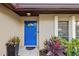 Bright blue front door with decorative glass and lush tropical plants at 1018 Deer Run, Venice, FL 34293