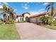 Tan house with a red tile roof and a large driveway. Lush landscaping surrounds the home at 10924 Bullrush Dr, Venice, FL 34293