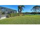 Green backyard with large grass area, hedges, palm trees, and a view of the water at 1330 Still River Dr, Venice, FL 34293