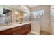 Bright bathroom featuring double sinks, cherry wood cabinets and a tiled walk-in shower at 1330 Still River Dr, Venice, FL 34293