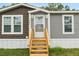 Steps leading to the front door of a manufactured home with a wood-tone deck at 12512 Hicks Rd, Hudson, FL 34669