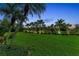 Lush green lawn in backyard bordered with palm trees and landscaping at 3408 Founders Club Dr, Sarasota, FL 34240
