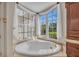 Bathroom featuring soaking tub with jets, large windows with natural light, and custom cabinets at 3408 Founders Club Dr, Sarasota, FL 34240