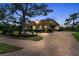 Expansive brick paver driveway leading to a beautiful home surrounded by manicured landscaping at 3408 Founders Club Dr, Sarasota, FL 34240
