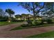 Beautiful home exterior with manicured landscaping, a brick driveway, and palm trees at 3408 Founders Club Dr, Sarasota, FL 34240