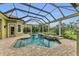 Screened-in pool with attached spa, surrounded by brick patio and green landscaping at 3408 Founders Club Dr, Sarasota, FL 34240