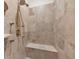 Elegant shower with stone-look tiles, built-in bench, and gold-toned fixtures at 3408 Founders Club Dr, Sarasota, FL 34240