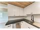 Modern kitchen features white cabinets, black countertops, and a stainless steel sink at 875 Royal Rd, Venice, FL 34293