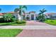 One-story home with red tile roof, palm trees, and a brick driveway at 25261 Spartina Dr, Venice, FL 34293