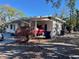 White single story home with carport, red car, and blue trash bin at 5443 Avenida Del Mare, Sarasota, FL 34242