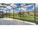 A screened in patio is looking out to a grass backyard with playset under a blue sky at 5548 Summit Gln, Bradenton, FL 34203
