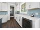 White kitchen with quartz countertops, a wine cooler, and light blue tile backsplash at 598 Lyons Ln, Longboat Key, FL 34228