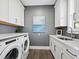 Bright laundry room with white cabinets, quartz countertops, and a stylish gray wall at 598 Lyons Ln, Longboat Key, FL 34228