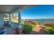 Relaxing waterfront patio featuring brick flooring, classic white columns, and lush tropical landscaping at 1249 S Basin Ln, Sarasota, FL 34242