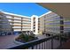 Courtyard view of condo building with parking and tropical plants at 1945 Gulf Of Mexico Dr # M2-206, Longboat Key, FL 34228