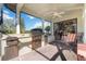 Covered outdoor kitchen with grill, cabinetry, and bar seating at 3706 80Th E Dr, Sarasota, FL 34243