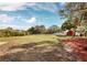 Large grassy backyard with a red building and mature trees at 3825 Sarasota Golf Club Blvd, Sarasota, FL 34240