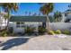 White single story home with green roof, landscaping, and a gravel driveway at 519 South Dr, Anna Maria, FL 34216