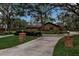 Brick ranch home with circular driveway, lush landscaping, and mature trees at 10616 Forest Run Dr, Bradenton, FL 34211