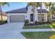 White one-story house with brown roof, landscaping, and a two-car garage at 249 Palmaria Ct, Nokomis, FL 34275