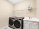 Practical laundry room includes modern washer and dryer, storage shelf, and a utility sink at 249 Palmaria Ct, Nokomis, FL 34275