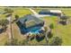 Aerial view of home with a backyard pool and a tiki hut, surrounded by a lush green lawn and mature trees at 25205 67Th E Ave, Myakka City, FL 34251