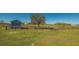 Horse property with a grass pasture and wooden fence in the foreground at 25205 67Th E Ave, Myakka City, FL 34251