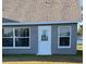 Gray house exterior with white trim, windows, and door. The house has a shingled roof and is surrounded by a grassy lawn at 4042 Kingsfield Dr, Parrish, FL 34219