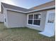 Gray house exterior with white trim, windows, and door. The house has a shingled roof and is surrounded by a grassy lawn at 4042 Kingsfield Dr, Parrish, FL 34219