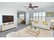 A staged living room with a white couch, gold accents, and a view into the bedroom at 4440 Tatum St, Port Charlotte, FL 33948