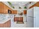 Bright kitchen with wood cabinets, white appliances, and floral wallpaper at 6713 Stone River Rd # 205, Bradenton, FL 34203