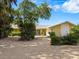 House exterior showcasing a yellow ranch house with a gravel driveway, lush landscaping, and a two car garage at 7916 Midnight Pass Rd, Sarasota, FL 34242