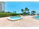 Community hot tub features tile trim and a stainless steel railing, surrounded by lounge seating and lush landscaping at 1102 Benjamin Franklin Dr # 407, Sarasota, FL 34236