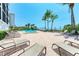 Resort-style pool area with palm trees and lounge chairs overlooking the sandy beach and ocean waters at 1102 Benjamin Franklin Dr # 407, Sarasota, FL 34236