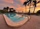 Community pool, complete with palm trees, lounge chairs and beach access, reflects the sunset at 1102 Benjamin Franklin Dr # 407, Sarasota, FL 34236