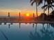 Community pool with palm trees reflecting the sunset sky at 1102 Benjamin Franklin Dr # 407, Sarasota, FL 34236