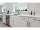 White kitchen with a sink, dishwasher, and view to backyard at 1621 Pine Bay Dr, Sarasota, FL 34231