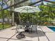 Screened patio with pool view, umbrella, and seating for six at 1621 Pine Bay Dr, Sarasota, FL 34231