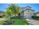 Two-story house with a large palm tree, landscaped lawn, and paver driveway at 17923 Polo Trl, Bradenton, FL 34211