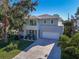 Contemporary two-story home with gray stucco, a two-car garage, a balcony, and lush landscaping at 2586 Prospect St, Sarasota, FL 34239