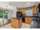 Kitchen with an island, wood cabinets, black appliances, and granite countertops at 3614 E 62Nd Ave, Bradenton, FL 34203