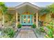 Home features a covered entry with teal double doors and lush landscaping at 414 Devonshire Ln, Venice, FL 34293